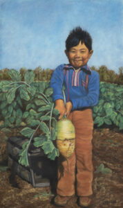 boy holding large harvested radish in field